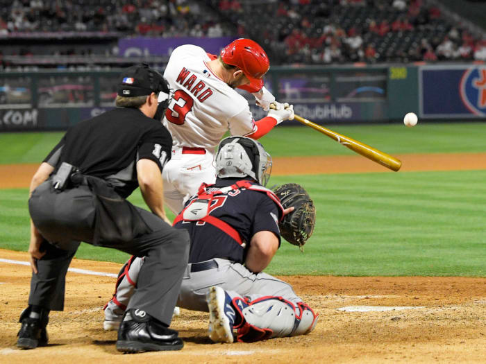 Los Angeles Angels’ Taylor Ward, center, hits a two-run home run as Cleveland Guardians catcher Austin Hedges, right, and home plate umpire Tony Randazzo watch during the seventh inning of a baseball game Monday, April 25, 2022, in Anaheim, Calif.